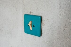 Schraubendreher und Spannungsprüfer neben einem geöffneten Lichtschalter an der Wand