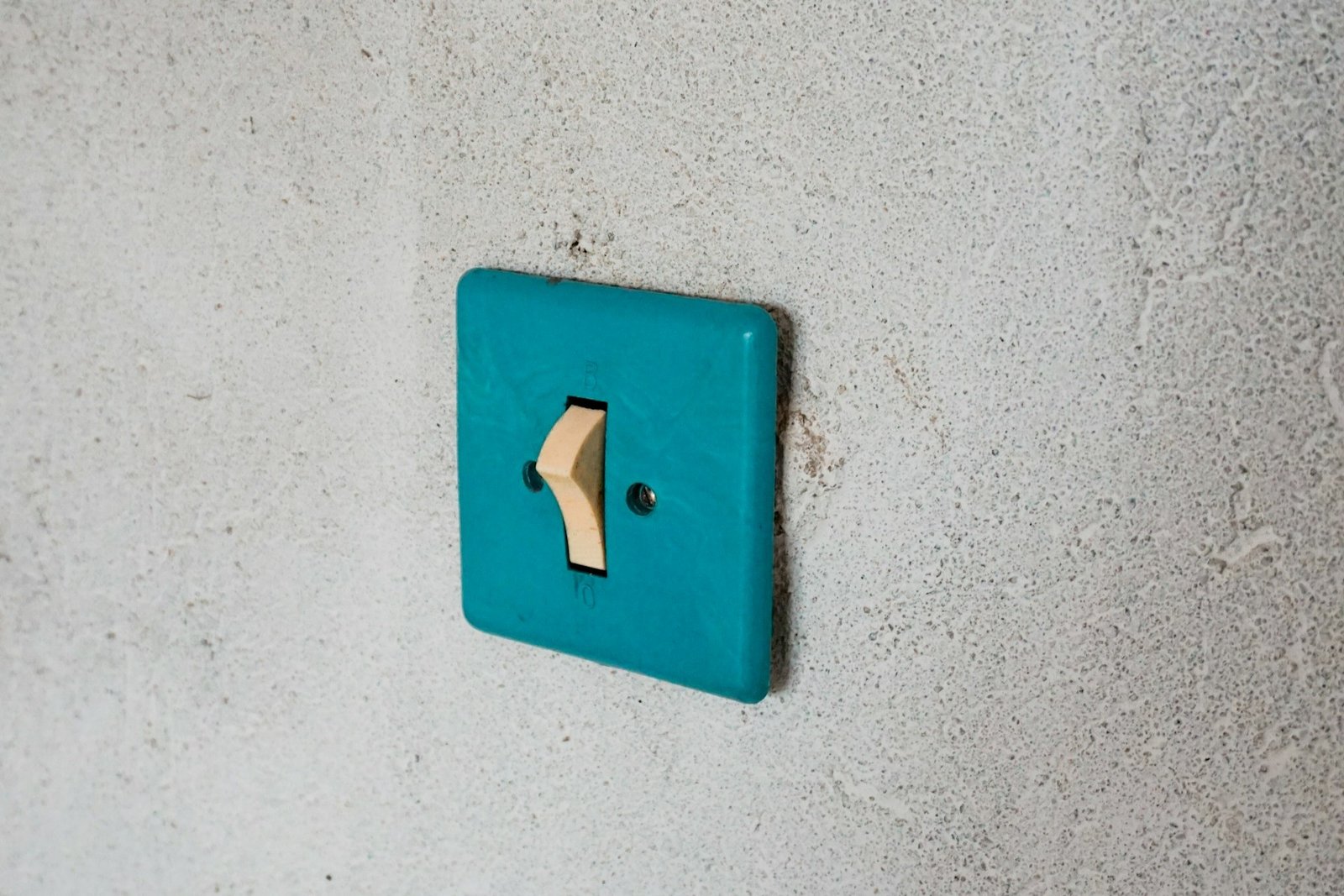 Schraubendreher und Spannungsprüfer neben einem geöffneten Lichtschalter an der Wand