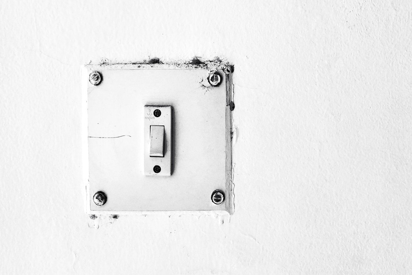 Lichtschalter mit Wippe in leicht schräger Mittelposition an einer Wand