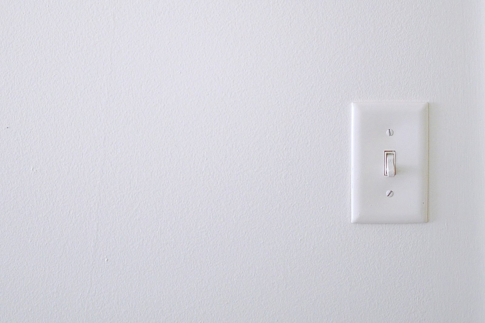 Lichtschalter mit Farbresten am Rahmen an einer frisch gestrichenen Wand