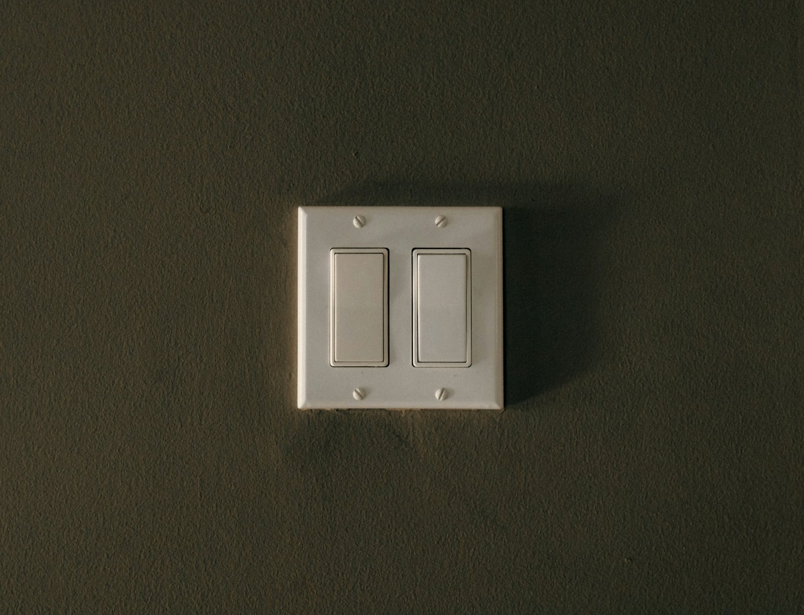 Geöffneter Lichtschalter mit sichtbarem Einsatz und Schraubendreher an der Wand