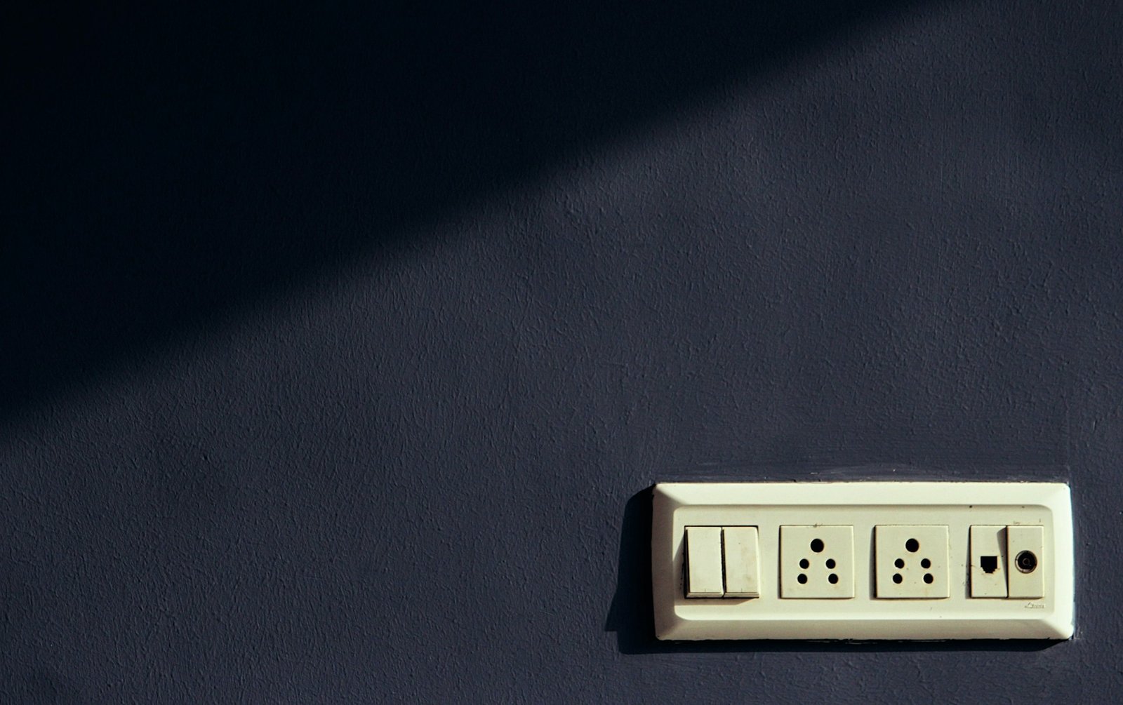 Spannungsprüfer an einem geöffneten Lichtschalter in einer Wand